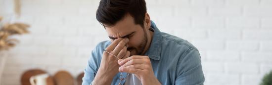 man achter computer wrijft in de ogen